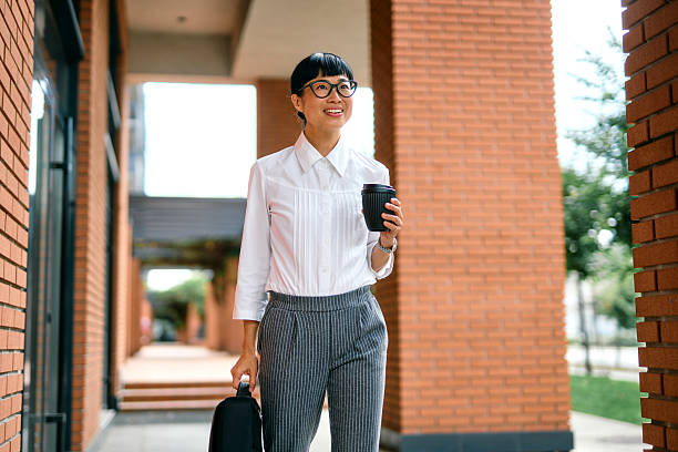 istock Businesswoman walking outdoors while holding coffee and backpack 2248354357
