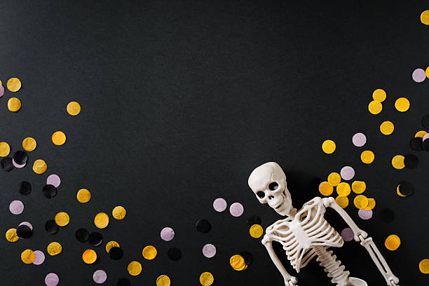 Colorful Halloween confetti and fun skeleton on dark background with empty space for text or design