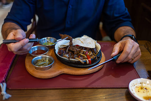 istock Man Eating Sizzling Meat and Vegetables 2248356260