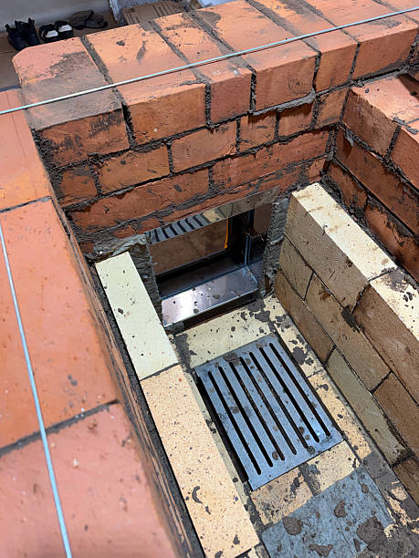 istock Formation of a fireclay core for a solid fuel furnace. A cast iron grate has been installed with the stove door in a frame box. Construction of a heating furnace. 2248359399