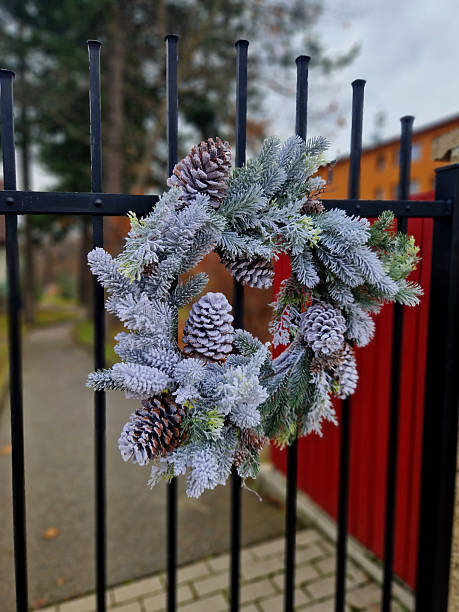 istock A conifer wreath is attached to a metal lattice gate. The surface is sprayed with a spray that creates artificial snow. 2248360724