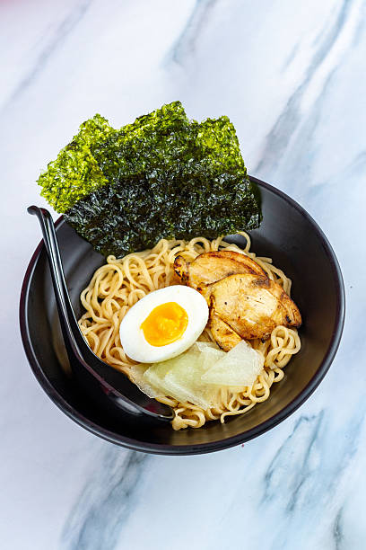 istock Ramen with egg noodles, char siu chicken, and fresh pickles, in a savory broth on a light background 2248361768