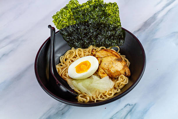 istock Ramen with egg noodles, char siu chicken, and fresh pickles, in a savory broth on a light background 2248361788