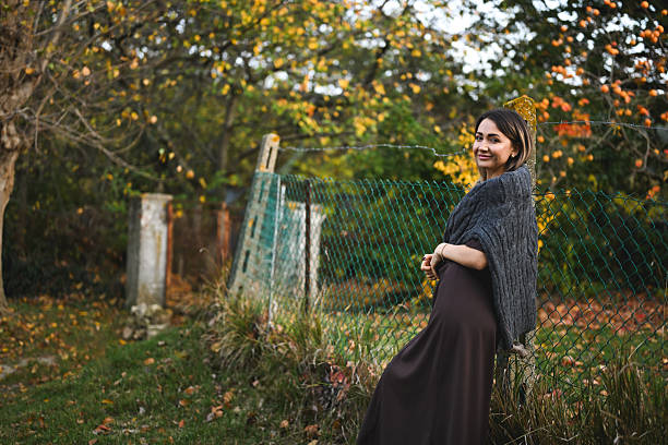 Woman smiling leaning on fence, enjoying autumn fashion and nature