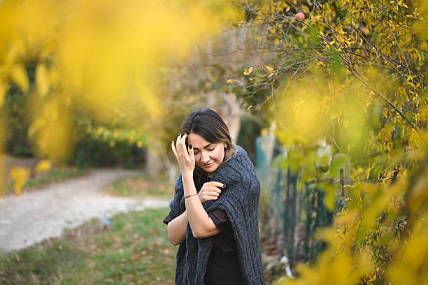 Pensive woman standing in a garden with colorful autumn foliage