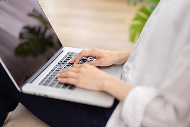 istock Close-Up of Woman's hands Typing on Laptop While Sitting on Sofa 2248365494