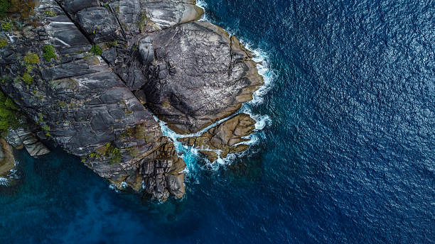 istock Massive Dark Granite Cliff and Tropical Forest Meeting the Deep Ocean 2248365582
