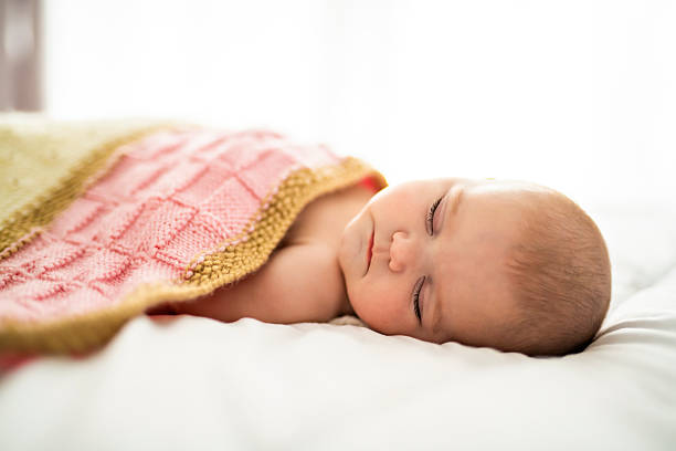 4 month baby sleeping on a white bed at home