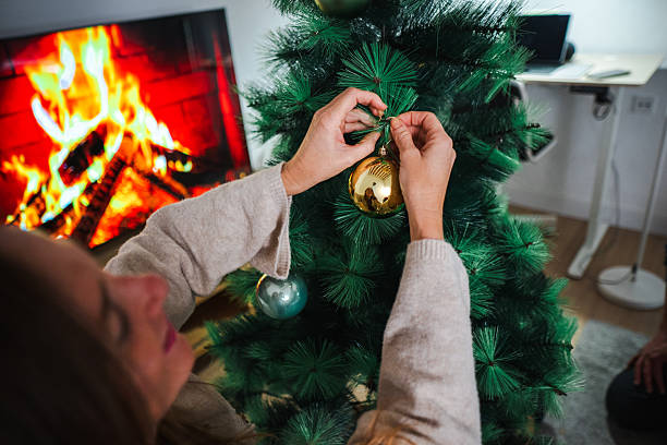 istock Woman decorating christmas tree near burning fireplace 2248368128