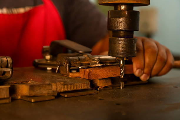 Violin making by hand bow. Close-up of an artisan's hands sanding or shaping a tool handle on a workbench. The image highlights craftsmanship, manual labor, and traditional woodworking or metalworking techniques. Music Instrument tool.