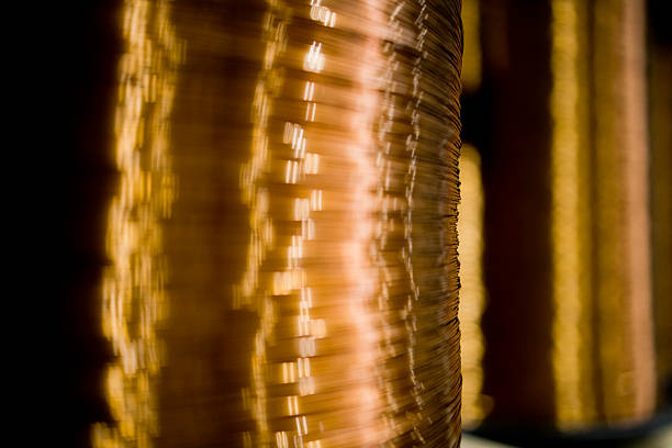 Abstract close-up view of a glowing metallic wire coil with golden reflections. The image creates a warm industrial and textured visual effect.