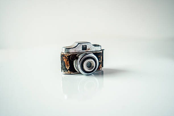 Miniature antique camera showing wear and tear on a reflective white surface