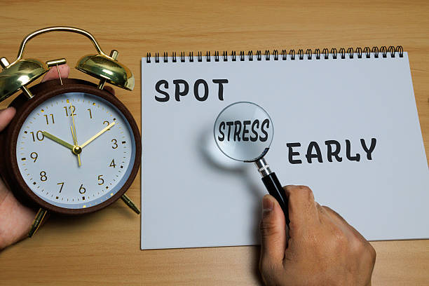 istock A classic alarm clock beside a notebook with the words “Spot Stress Early” 2248373703