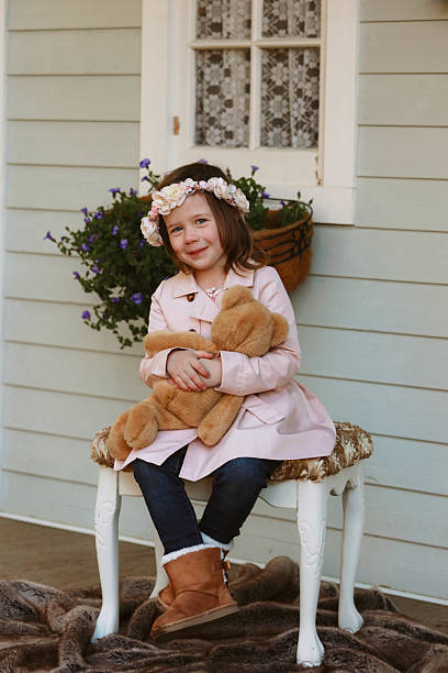 A little girl, four years old, on a rustic porch, holding her teddy bear. Shot with a Canon 5D Mark IV.