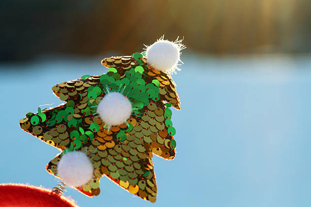 A red headband adorned with gold sequins and Christmas decorations in the winter snow.
