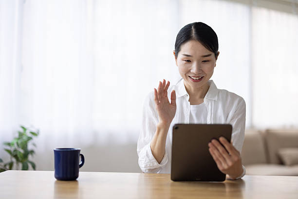 istock Smiling Woman Video Chatting on Tablet at Table 2248375017