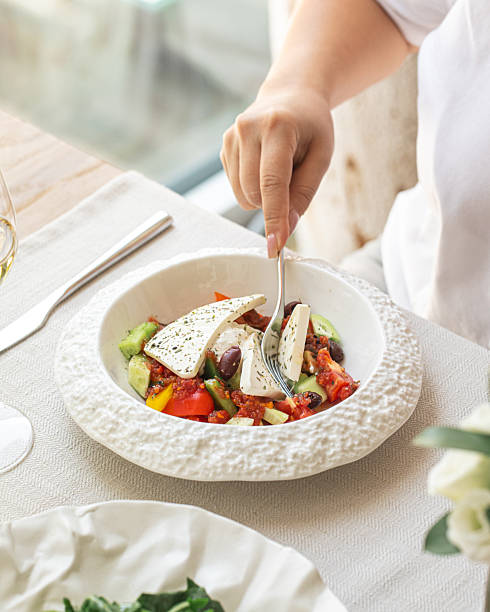 Woman eating Greek salad with feta and vegetables