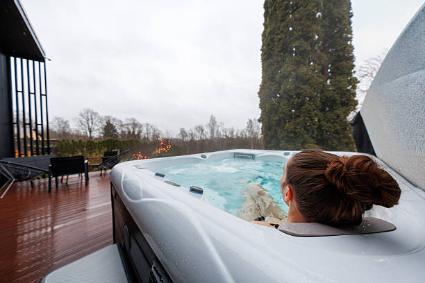 istock Rainy day hot tub on deck beside modern black slat building 2248375132