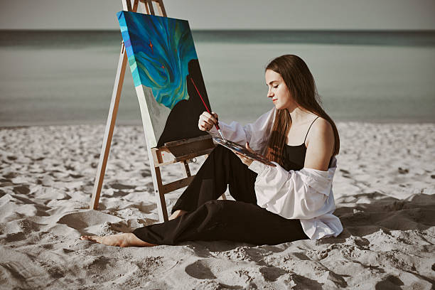 istock Young female painter creating art on serene beach 2248375390