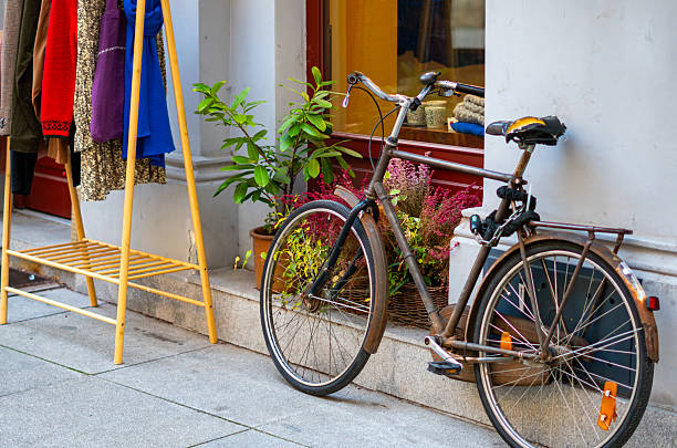 istock Clothing rack displayed outside a shop beside a decorative bicycle surrounded by plants in a cozy urban setting 2248377122