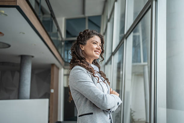 istock Confident businesswoman smiling, looking out office window 2248377365