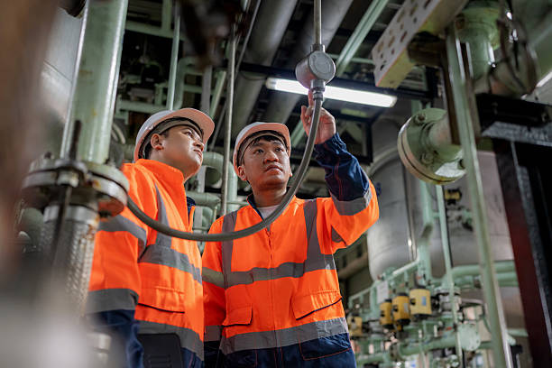 istock Two engineers in protective workwear stand on a production line examining pipelines and machine valves discussing design improvements and operational efficiency for storage tanks oil production platforms and refinery systems 2248377664
