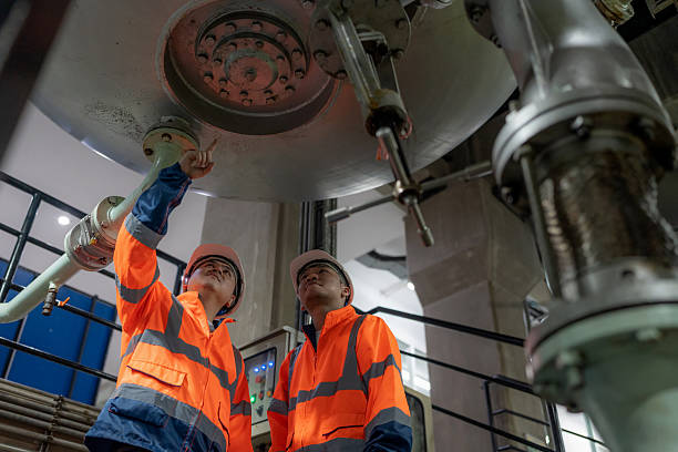 istock Mechanical engineers in protective workwear stand on the production line discussing pipelines machine valves and storage tanks They use digital devices to analyze systems plan improvements and enhance efficiency safety and sustainability in oil production 2248377665