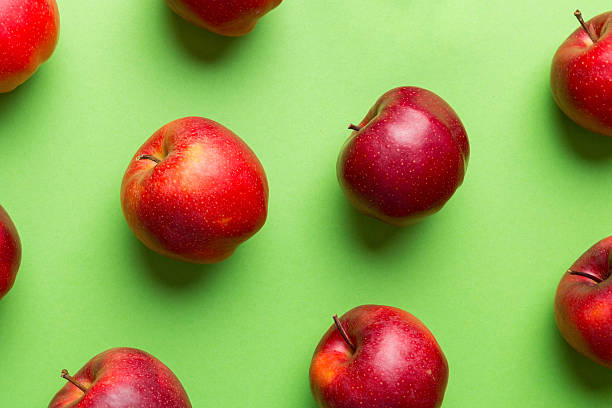 Many red apples on colored background, top view. Autumn pattern with fresh apple above view.