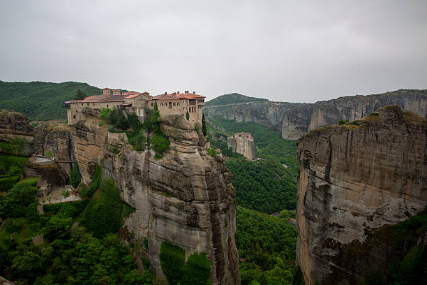 Unesco world heritage site meteora monasteries perched on impressive rock pillars overlooking the lush valley, representing rich greek history and culture. Meteora, greece