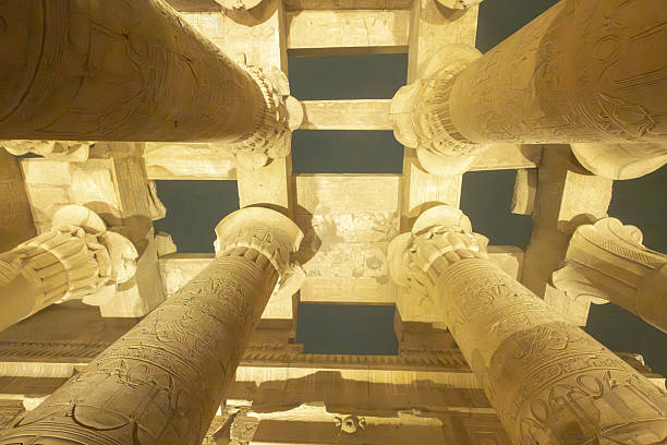 Egyptian temple columns show hieroglyphics and architecture lit up against a dark sky