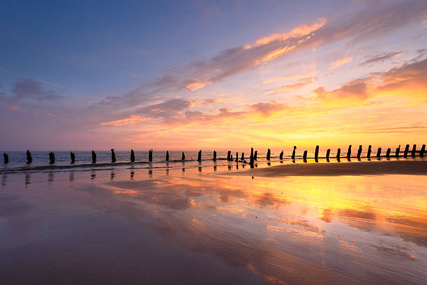 Old sea defence groynes used to protect coastlines from erosion at sunset. Walney, Lake District, UK.