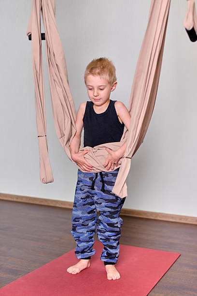 istock Young boy engaging with aerial hammock in bright room 2248383246
