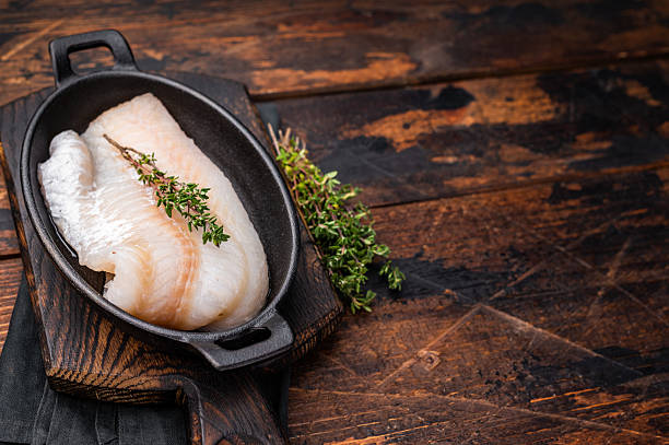 istock Pristine raw cod fillet, waiting to be marinated and cooked to perfection for a delightful dining experience. wooden background. top view 2248383780