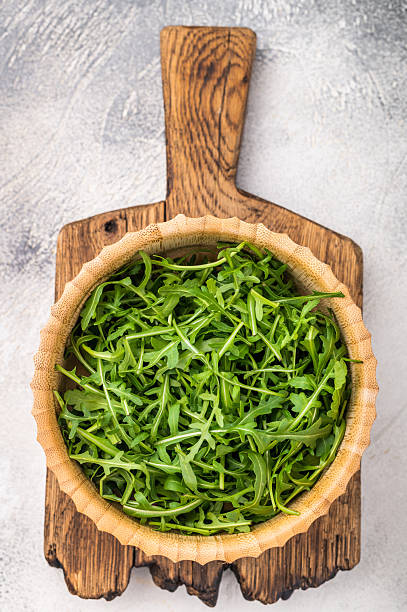 Fresh arugula leaves, vibrant and peppery, perfect for adding a zesty touch to salads and sandwiches. grey background. top view