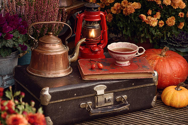 Beautiful flowers and cup of tea and ketle, autumn decor with lantern and pumpkins