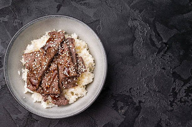 Yakiniku, wagyu marbled beef cuts and rice in a bowl. A culinary journey that captures the essence of Japanese grilling traditions. black background. top view