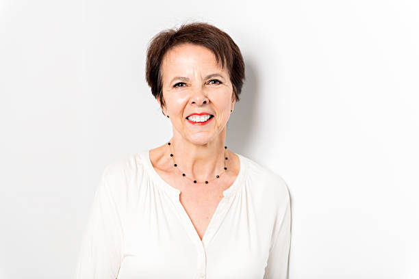 Portrait of mature 55 - 60 year old woman with grey hair, arms crossed