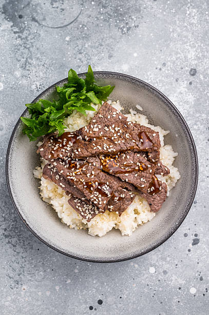 Delectable yakiniku feast, featuring a variety of marbled beef cuts and rice. A culinary journey that captures the essence of Japanese grilling traditions. grey background. top view