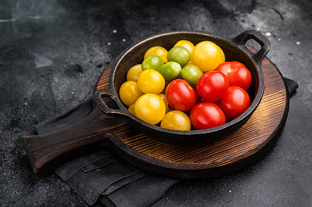 istock Uncooked small tomatoes. red, green and yellow cherry tomatoes assortment, cocktail mix. black background. top view 2248387424