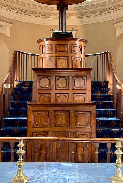 istock An ornate, tiered wooden pulpit rises elegantly within a circular hall, featuring rich paneling, blue-carpeted steps, and brass details that highlight its historic craftsmanship and solemn grandeur. 2248388440