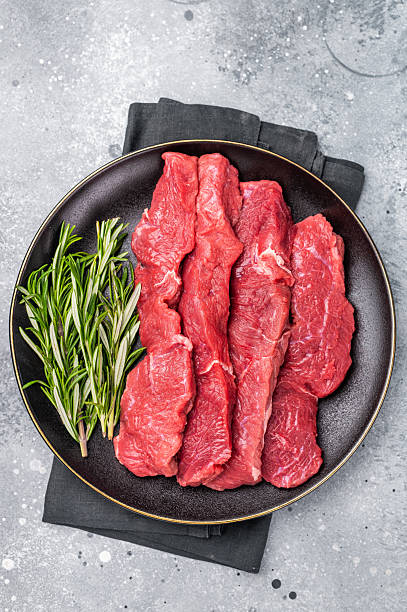 istock Raw bison meat presented with fresh herbs and spices, inspiring bold flavors and unique recipes for adventurous food lovers. grey background. top view 2248389546