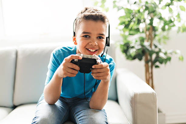 istock black boy play video game on sofa with headset 2248391508
