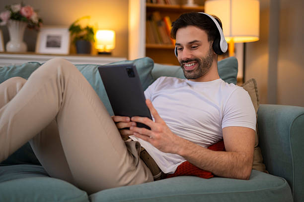 istock Young adult man relaxing on sofa with digital tablet 2248394809