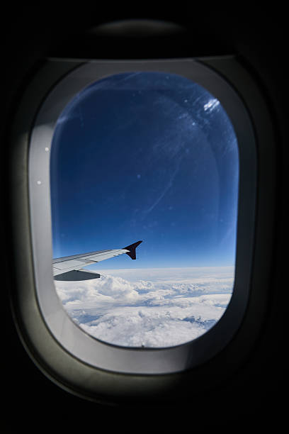 istock View from an airplane window over clouds, wing tip in frame, blue sky and horizon 2248395539