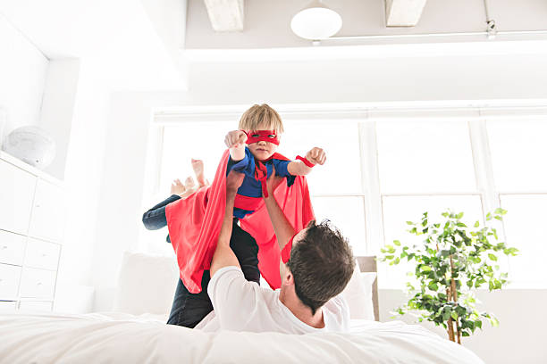 istock Father and son play superheroes on bed at home 2248395568