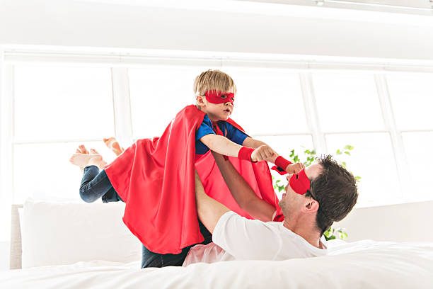 istock Father and son play superheroes on bed at home 2248395589