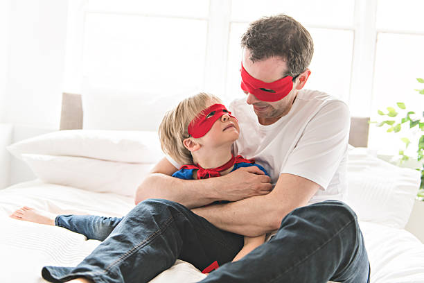 istock Father and son play superheroes on bed at home 2248395644