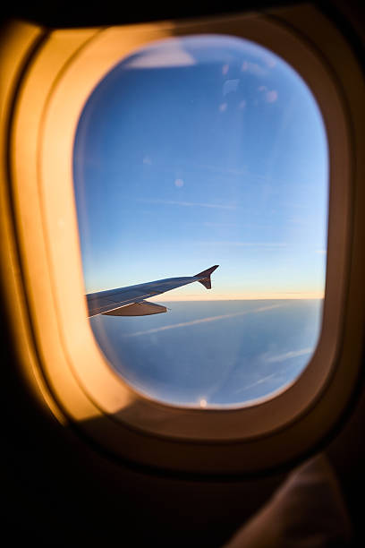 istock View from an airplane window of the wing tip against a blue sky at sunset 2248397356