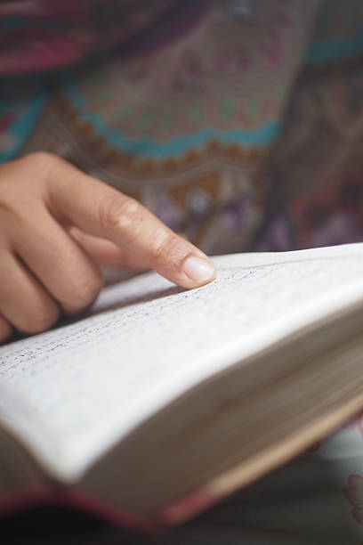 istock Person reading a quran while pointing to the text 2248398033