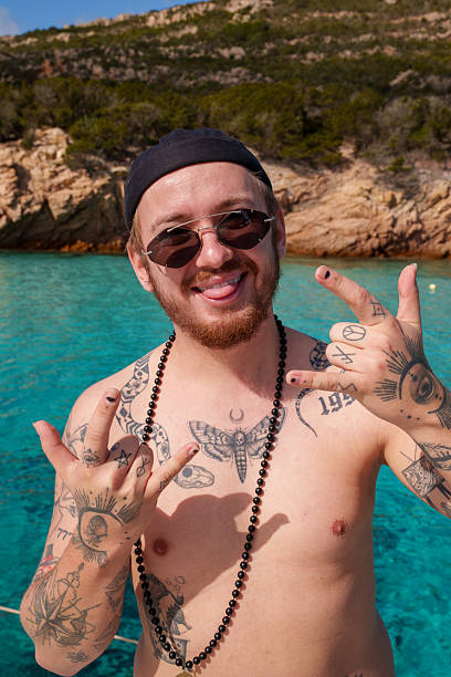 Summer vacation on a tropical beach. Man with tattoos enjoying is time by the turquoise sea of Italy